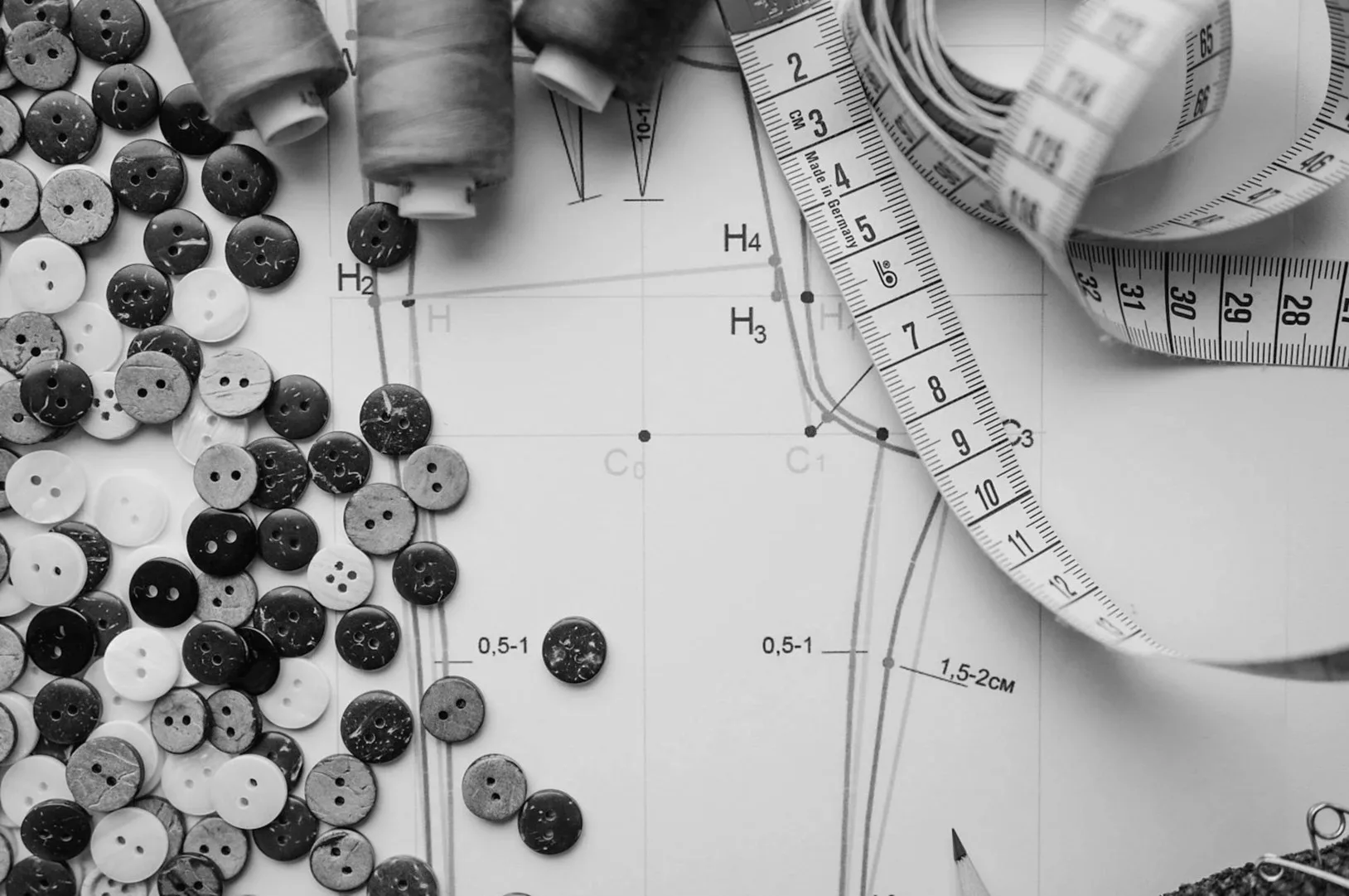 Tape measure, buttons and a drafted pattern on paper