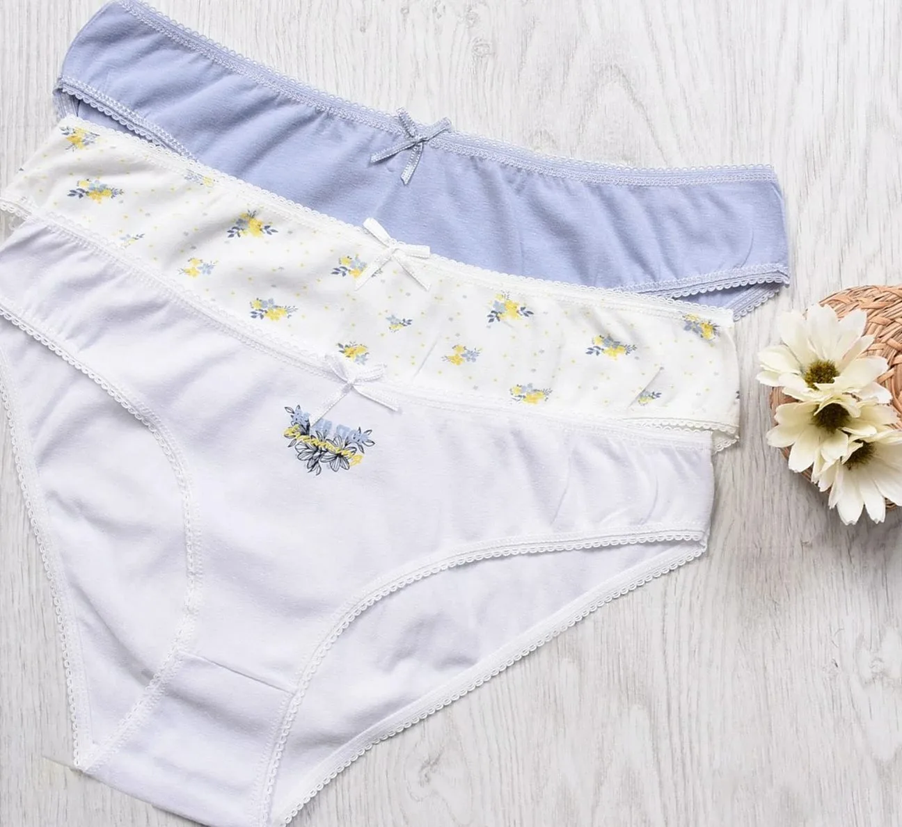Three pairs of cotton briefs laid flat on a white wooden board